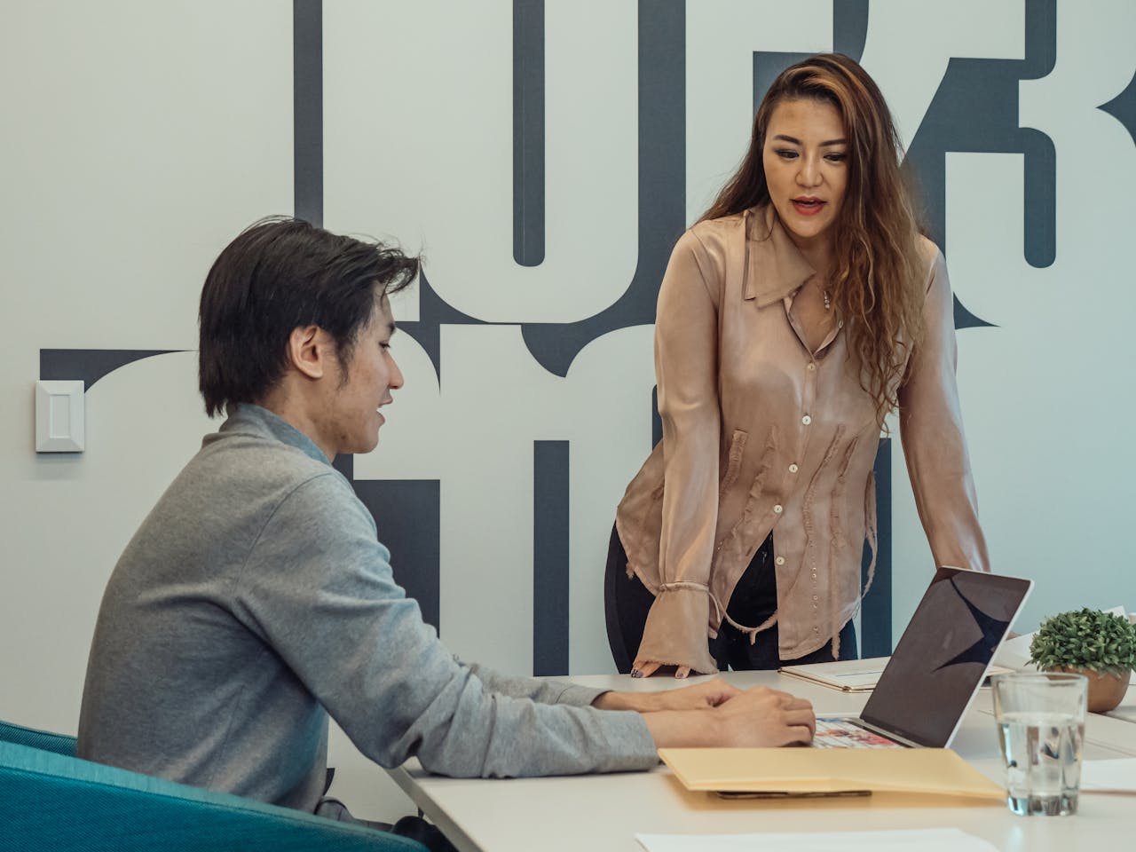 Colleagues discussing a project around a laptop in a modern office setting.